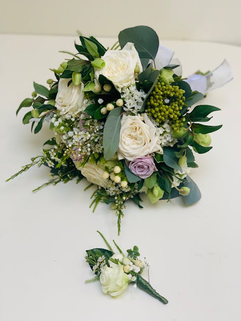 A close-up image of a fresh bridal bouquet featuring cream and pale lavender roses, complemented by small white filler flowers like baby's breath, and green foliage including eucalyptus leaves with a 